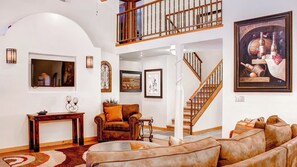A spacious living room with a high ceiling, a staircase, and a large painting. - Hacienda in Solitude Vineyard by Avantstay Vineyard Views + Patio Paso Robles (Paso Robles)