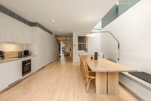 Eine moderne Küche mit einem langen Holztisch und Stühlen, einem eingebauten Backofen und einer Essecke mit einer Bank.