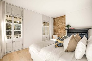 A bedroom with a bed, a fireplace, and a stone wall. - Palmer Darlinghurst - Stunning Terrace Home (Darlinghurst)