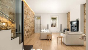 Una sala de estar moderna con una pared de piedra decorativa, una chimenea y un ventanal grande.