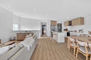 Una cuina moderna amb una illa central, armaris de fusta i una zona de menjador amb taula i cadires de fusta.