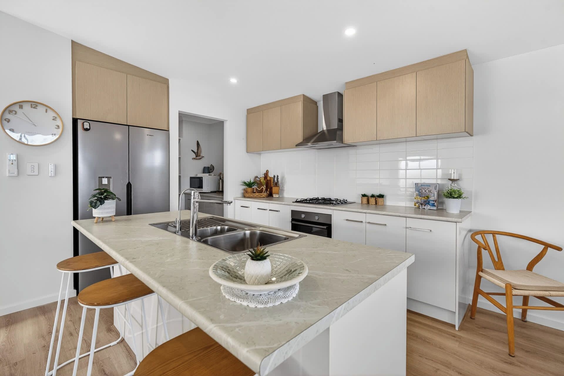 A modern kitchen with a central island, stainless steel appliances, and light wood cabinetry.
