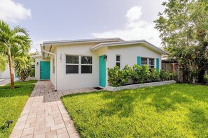 A single-story house with a paved driveway, a green door, and a number '201' on the wall. - Sunny Apartment in Quiet Lush Neighborhood (Wilton Manors)