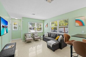 Ein Wohnzimmer mit einer Couch, Sesseln, einem Couchtisch und einem Fernseher.