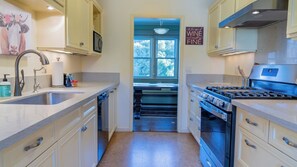 Une cuisine équipée d’un évier, d’une cuisinière et de placards.