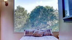 A bedroom with a large window, a bed with patterned bedding, and a view of trees outside. - Vin Rouge 51 by Avantstay Sleeps 8 + Hillside Deck + Ping Pong 15-min Walk to Downtown (Paso Robles)