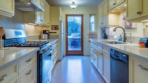A kitchen with a stove, oven, refrigerator, and a view of a barbecue grill outside. - Vin Rouge 51 by Avantstay Sleeps 8 + Hillside Deck + Ping Pong 15-min Walk to Downtown (Paso Robles)