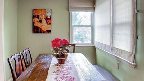 Un coin repas avec une table en bois, des chaises, une plante en pot et un tableau accroché au mur.