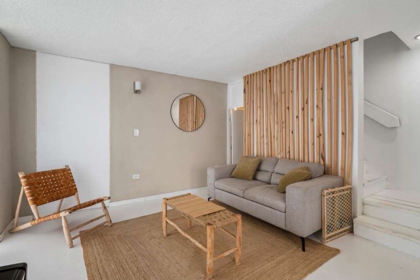 Una sala de estar con un sofá, una mesa de centro y un sillón de mimbre.