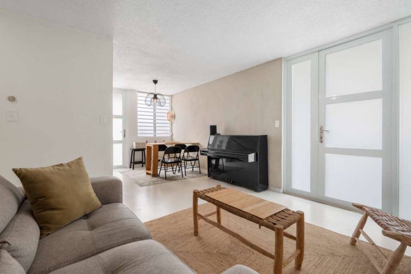 A living room with a sofa, a coffee table, a fireplace, and a dining area with chairs and a table.