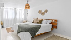 Ein Schlafzimmer mit einem Bett, einer Pendelleuchte und einer Wanddekoration.