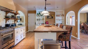 Una cocina amplia con una isla central, estufa y comedor con sillas.
