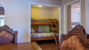 Ein Zimmer mit einem Etagenbett, einem Holztisch und zwei Stühlen.
