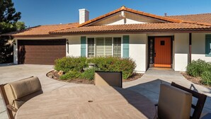 Ein Wohnhaus mit Garage, einer Veranda mit Stühlen und einem kleinen Garten.