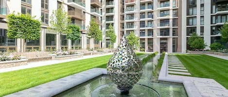 A modern building with a central water feature and well-maintained greenery.