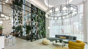 Eine moderne Lobby mit Sitzgelegenheit, einer Pflanzenwand und einem großen Fenster.