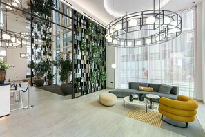 Eine moderne Lobby mit Sitzgelegenheit, einer Pflanzenwand und einem großen Fenster.