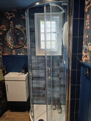 A bathroom with a glass shower enclosure, a white sink, and a decorative mirror.