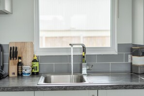A kitchen with a stainless steel sink, a window above it, and a knife block on the counter.
