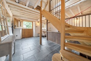 Un intérieur spacieux avec un escalier en bois, un coin cuisine et une vue par la fenêtre.