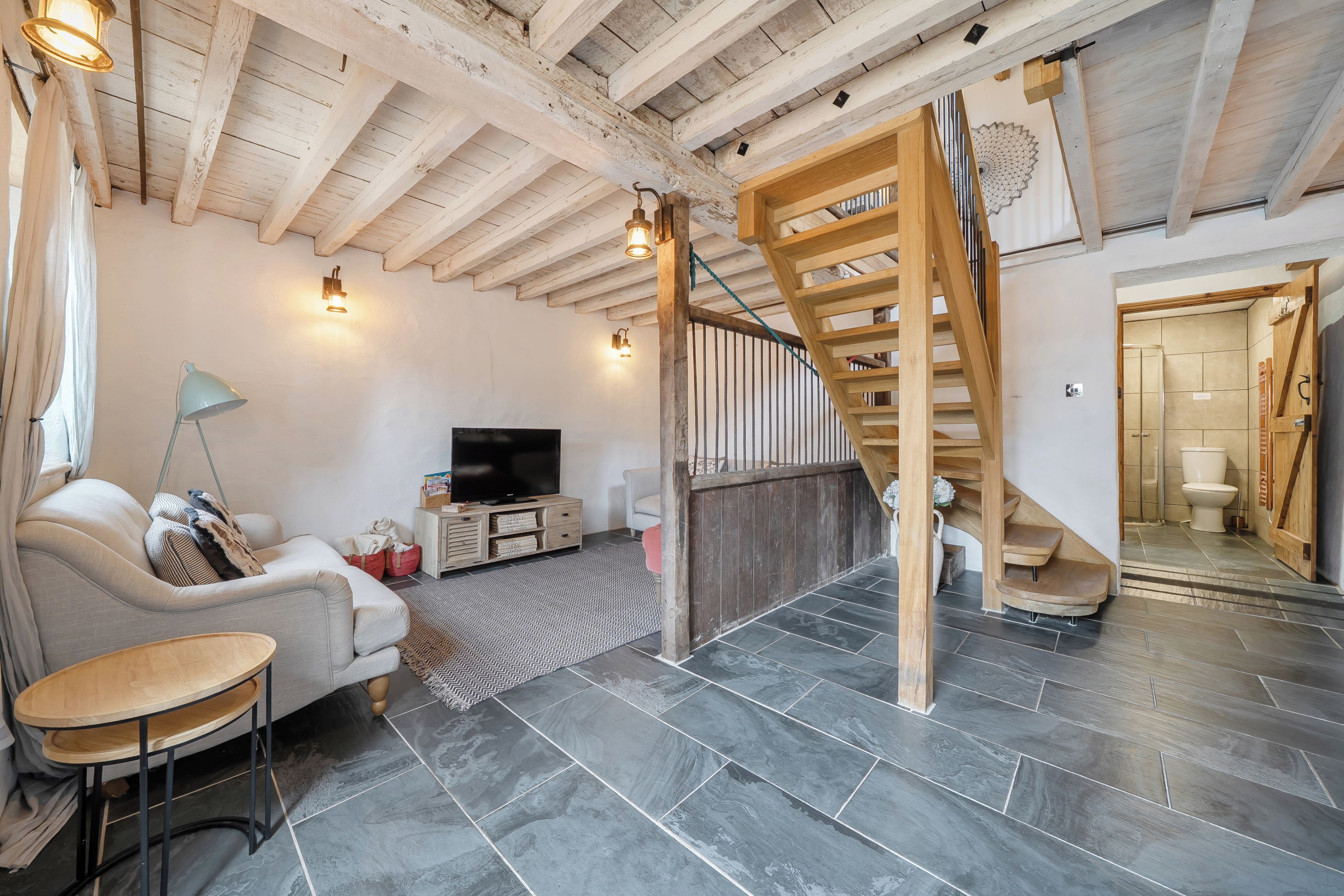 Un salon moderne avec un téléviseur, un canapé et un escalier en bois.