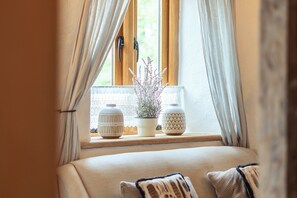 A window with curtains, a sofa, and two vases on a windowsill.