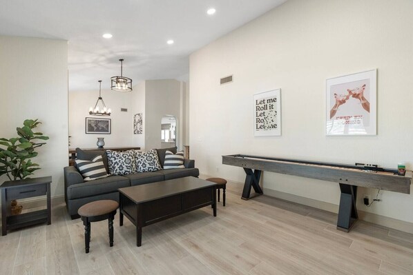 A living room with a sofa, coffee table, and a pool table.