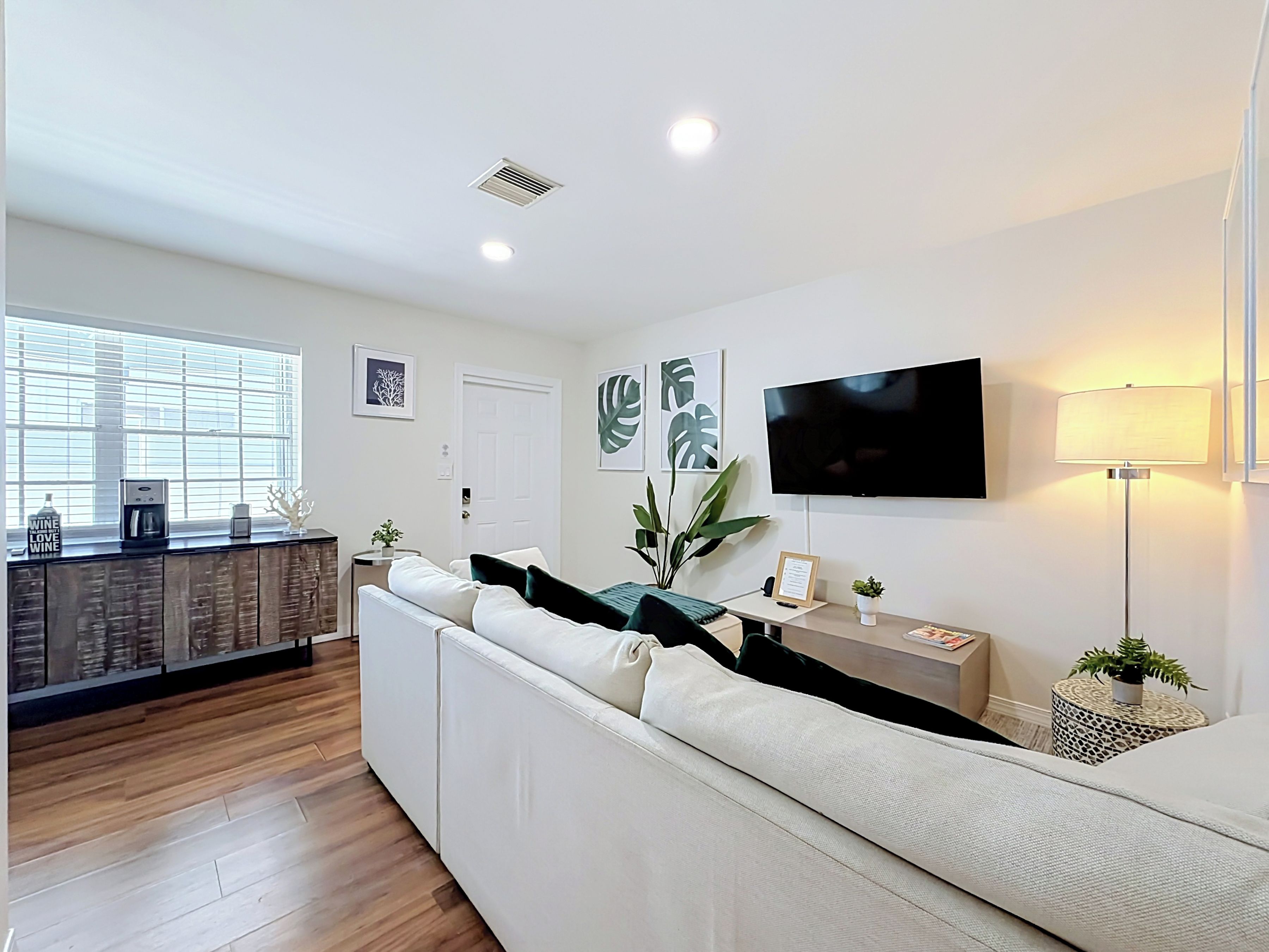 Uma sala de estar moderna com sofá, cafeteira, televisão e planta.
