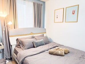 En pænt redt seng med en sengegavl, en læselampe og et natbord med lampe.