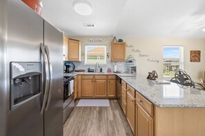 Eine moderne Küche mit Holzschränken, einem Edelstahlkühlschrank und einer Arbeitsplatte aus Granit.