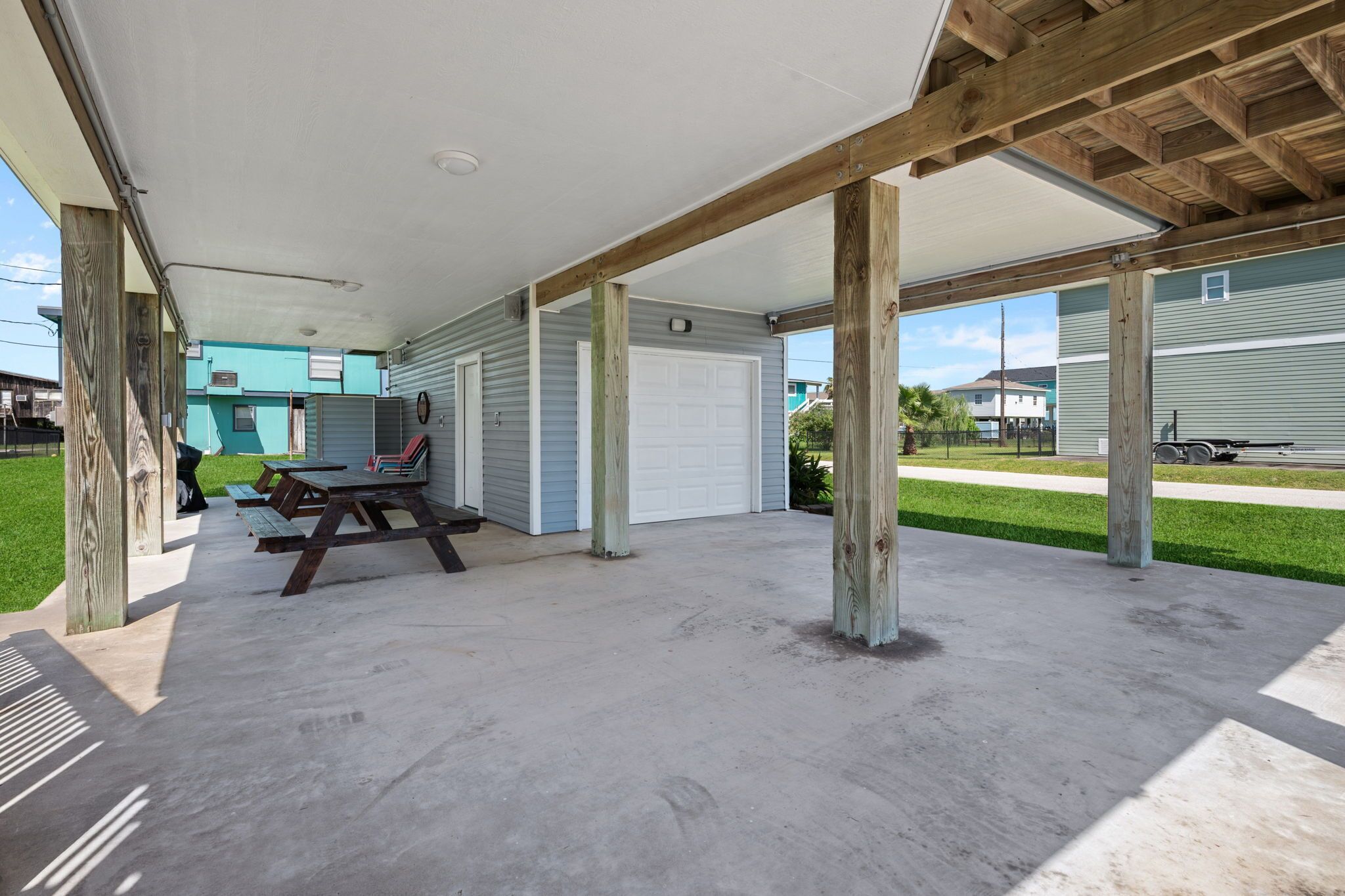 A covered outdoor area with concrete flooring, wooden beams, and a picnic table.