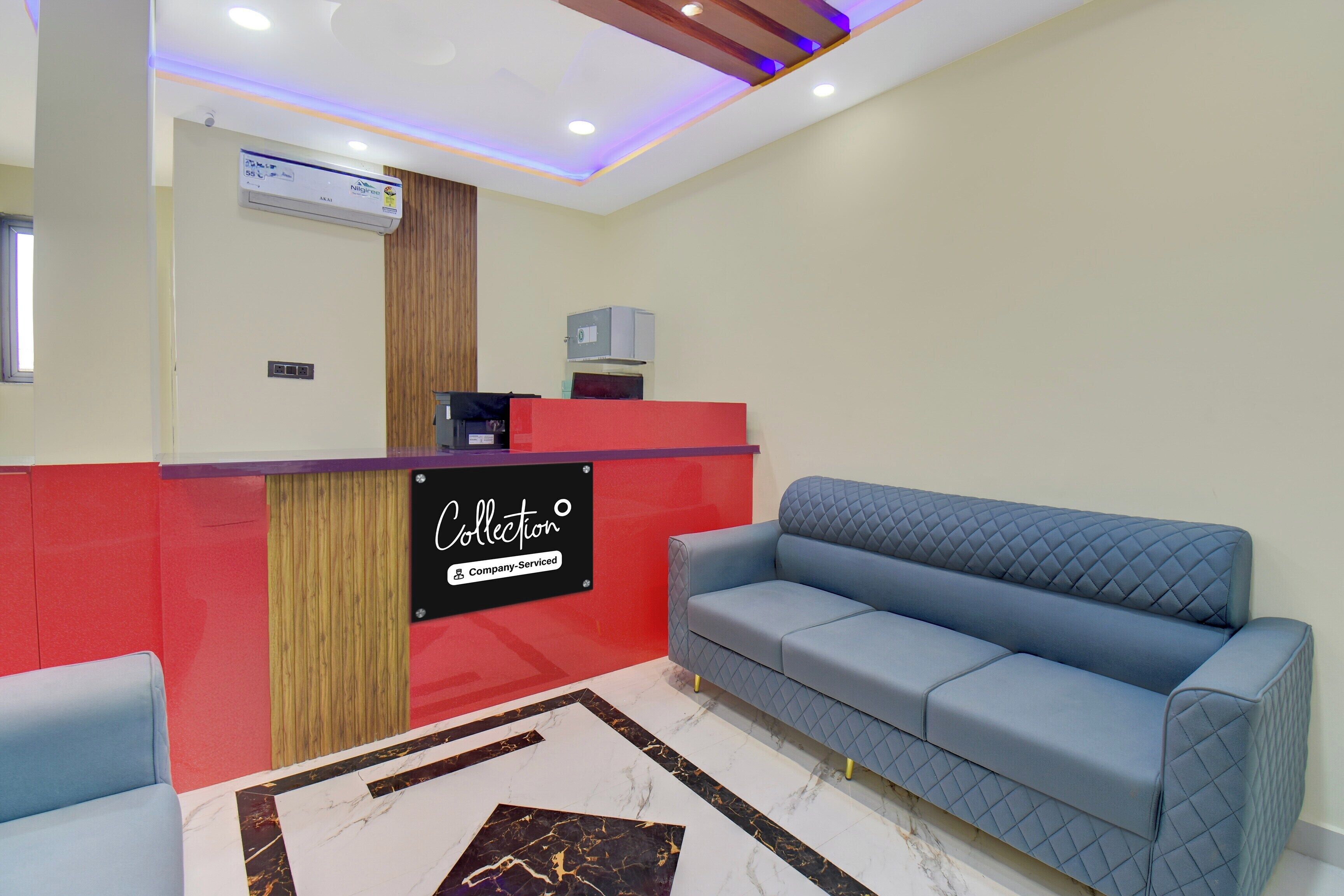 A reception area with a red counter, a blue sofa, and a marble-patterned floor.