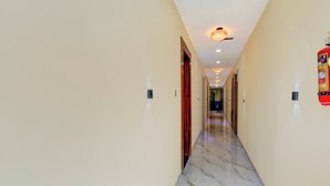 A hotel corridor with marble flooring, recessed lighting, and doors on both sides. - Super Collection O MIDC Pimpari Pune (Pune)