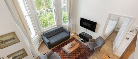 A modern living room with a sofa, two armchairs, a coffee table, and a flat-screen TV.