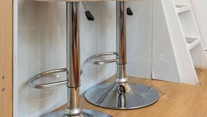 Two white bar stools with chrome bases, a white ladder, and a white shelf with small potted plants. - GuestReady - Charming Loft in Vibrant London (London)