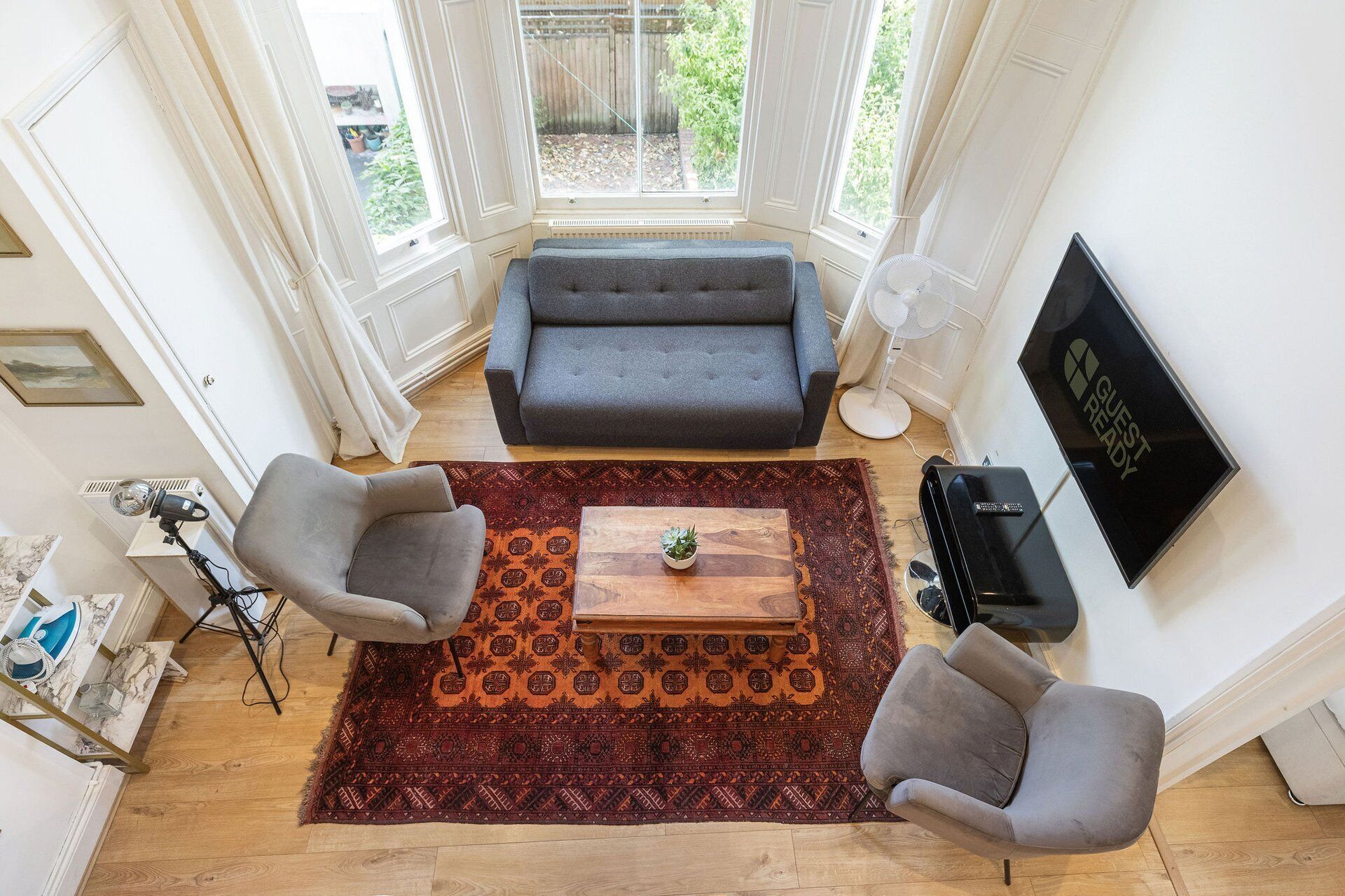 A living room with a sofa, two armchairs, a coffee table, a TV, and a large window.