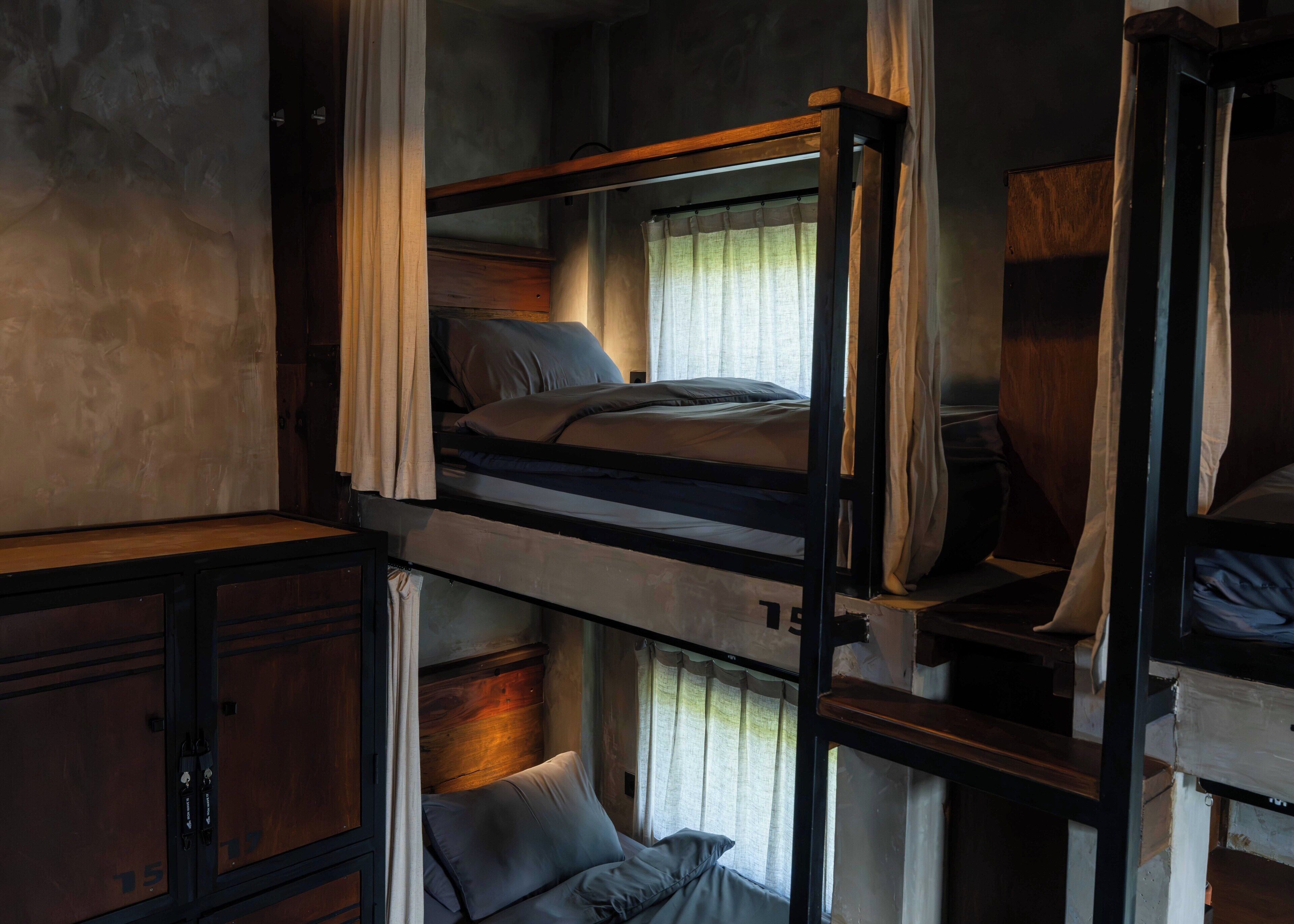 Una stanza con un letto a castello, una scrivania, una sedia, tende e una finestra.