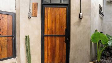 Una puerta de madera con marco negro, un letrero en la pared y una planta en maceta.