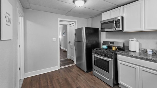 A modern kitchen with stainless steel appliances, a microwave, and a granite countertop.