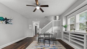 A modern interior with a dining area, staircase, and a ceiling fan.