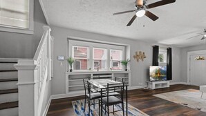 A dining area with a table and chairs, a ceiling fan, and a window with blinds.