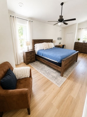 A bedroom with a bed, a nightstand, a dresser, a chair, and a ceiling fan. - Cozy 1 bedroom cottage, walk to famous Sponge Docks (Tarpon Springs)