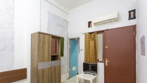Une chambre d’hôtel avec un placard, une petite table sur laquelle se trouve un téléviseur, et une porte dont le cadre est marron.