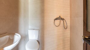 A bathroom with a toilet, a sink, and a shower area.