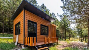 Una cabaña de madera con balcón, ubicada en un área boscosa.