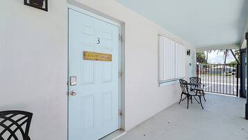 Une porte blanche avec un numéro, une enseigne et une petite fenêtre.