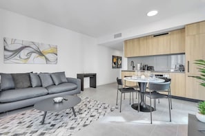 A modern living room with a grey sofa, a coffee table, and a dining area with a round table and chairs. - Cozy 1-bedroom condo in gorgeous Miami (Miami)