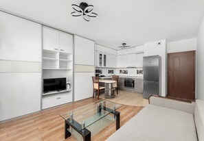 Una cuina moderna amb armaris blancs, un refrigerador Bosch i una zona de menjador amb taula i cadires de vidre.