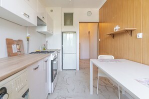 Una cocina compacta con estufa, refrigerador y comedor con mesa.