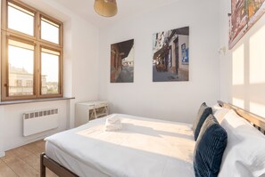 A bedroom with a bed, a radiator, a desk, and a window. - Kazimierz Riverside Charming Apartment (Kraków)